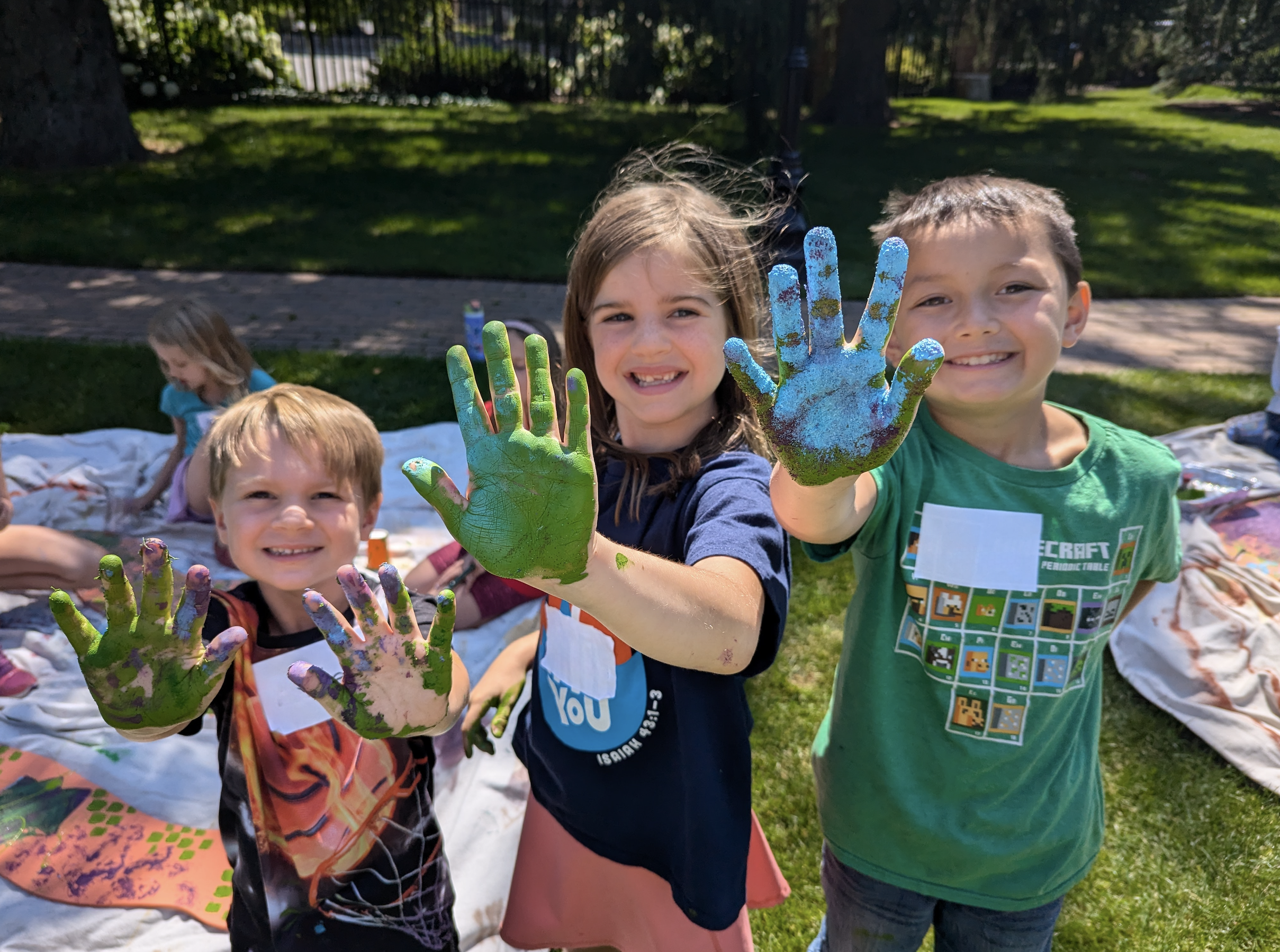 Three Summer Art Session participants with "painty hands" after creating a sculpture together.
